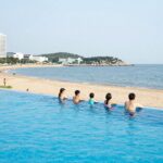 양양 비치펜션의 넓은 수영장 전경으로 가족 단위 여행객이 물놀이를 즐기고 있다