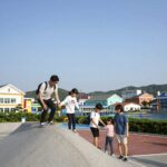 여수 유월드 루지 테마파크에서 루지를 타고 내려오는 가족의 모습, 스릴 넘치는 코너 구간